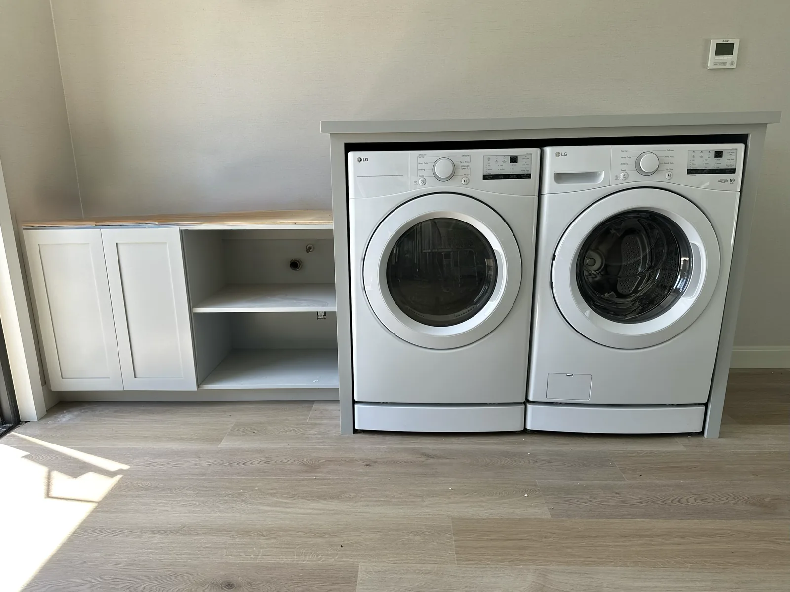 White laundry cabinetry with a counter running over the machines in Atherton
