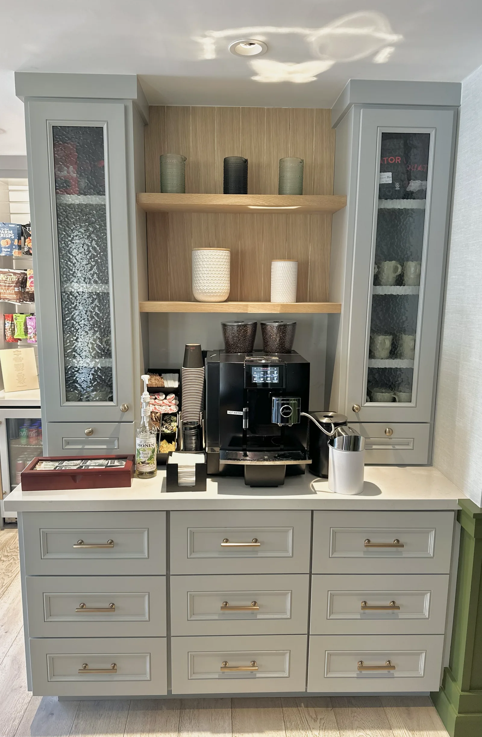 Office coffee bar with glass front uppers and oak floating shelves in Atherton