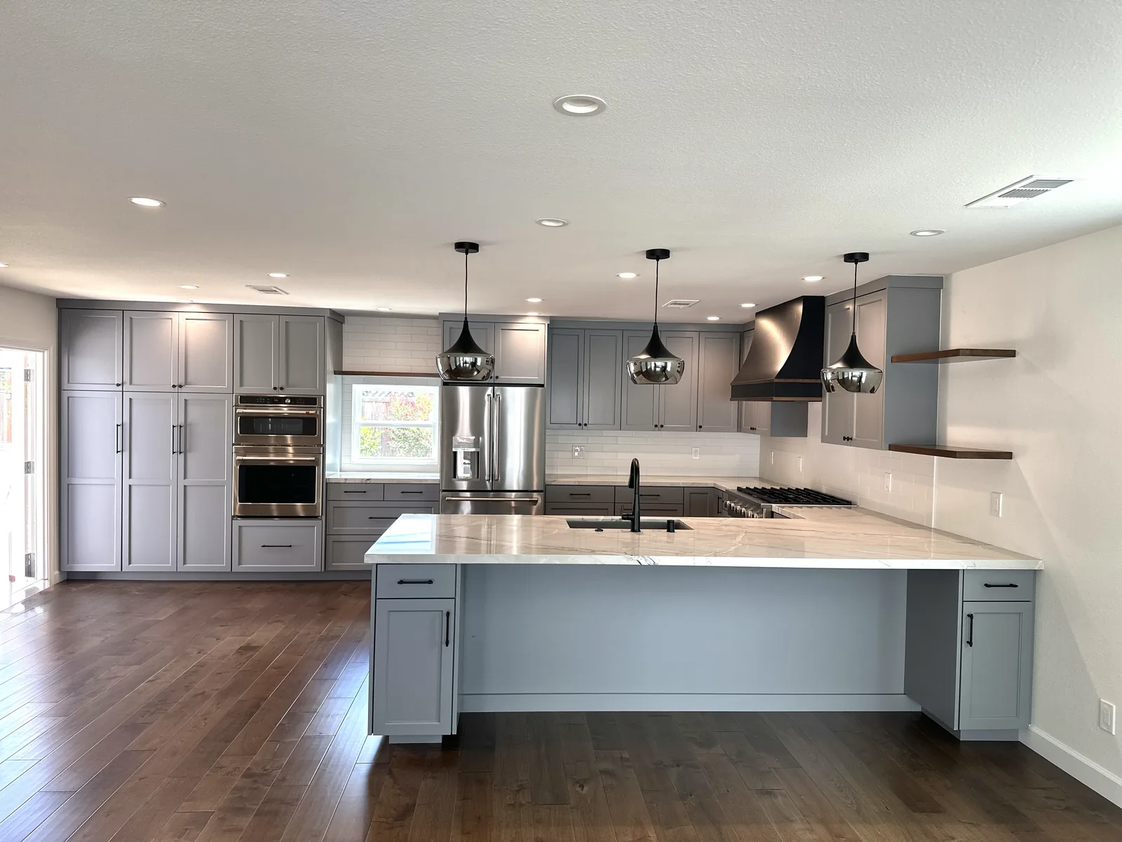 Grey shaker kitchen with a peninsula and stacked double ovens in Fremont