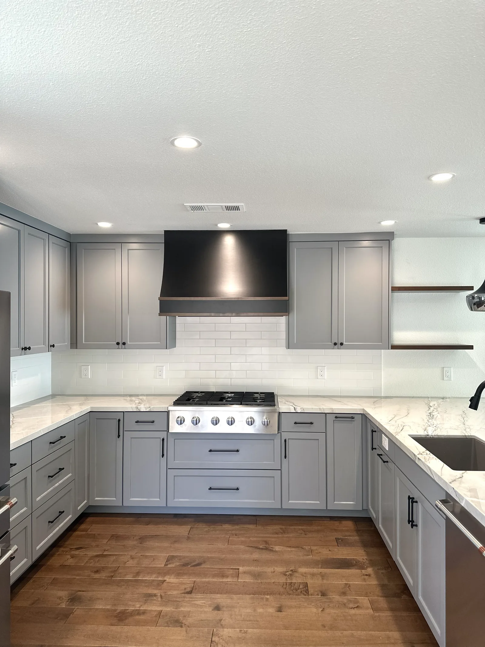 Grey shaker kitchen with a black range hood and quartz counters in Fremont