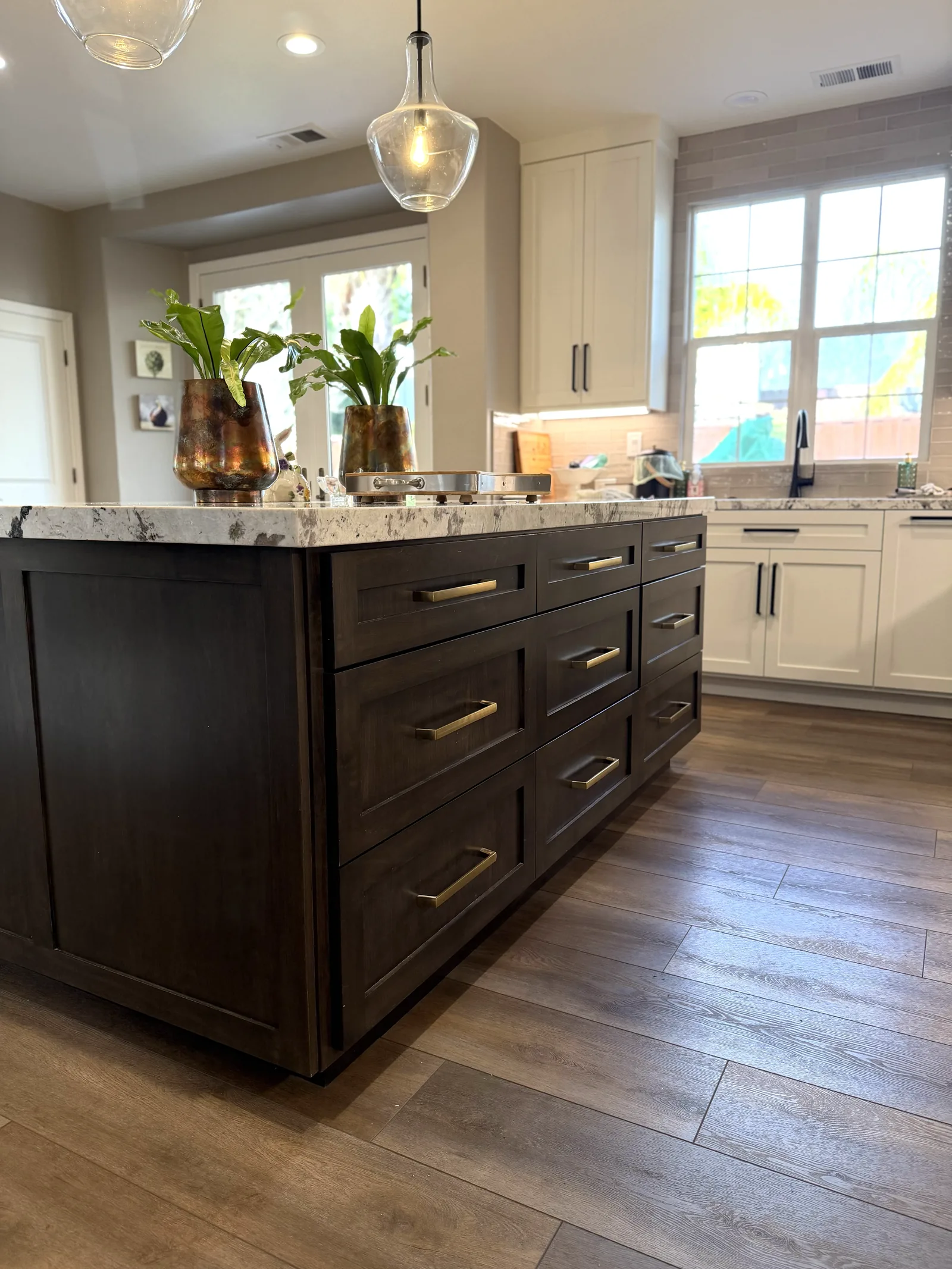 Dark stained kitchen island with brass pulls against a white perimeter in Gilroy