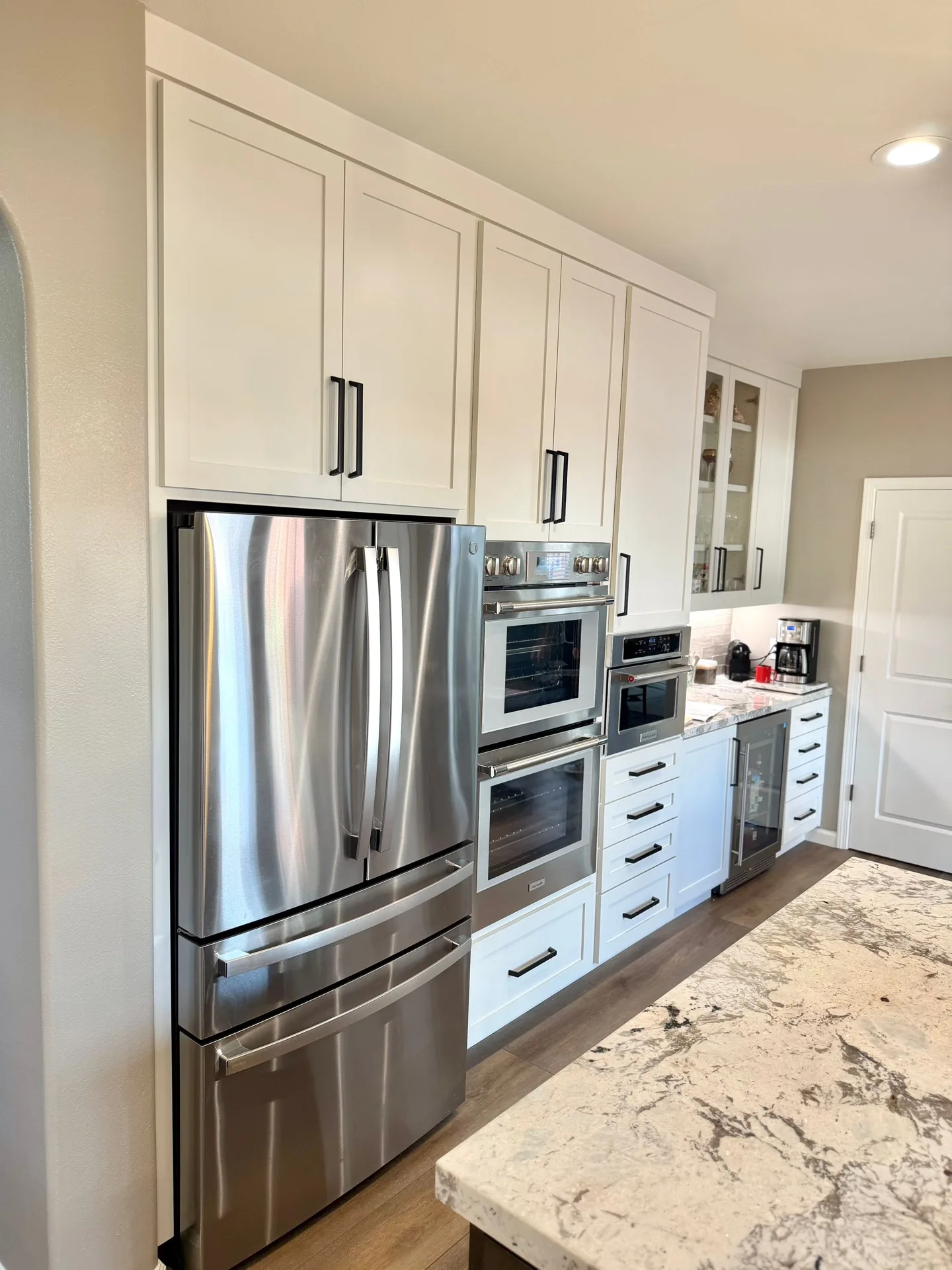 White shaker kitchen with a panelled refrigerator and double wall ovens in Gilroy