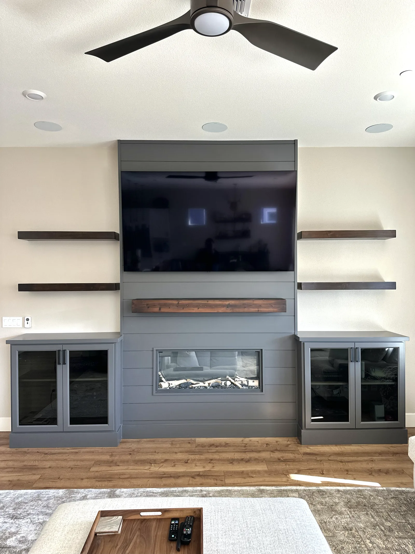 Entertainment center with a fireplace surround and floating walnut shelves in Hollister