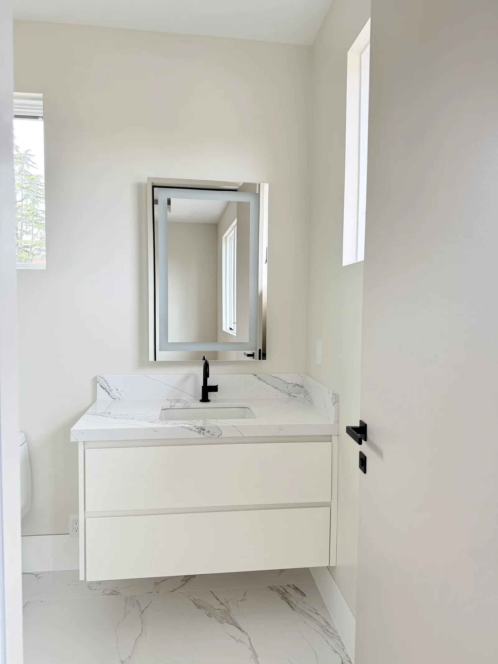 White floating vanity with a marble-look quartz top and lit mirror in Los Altos