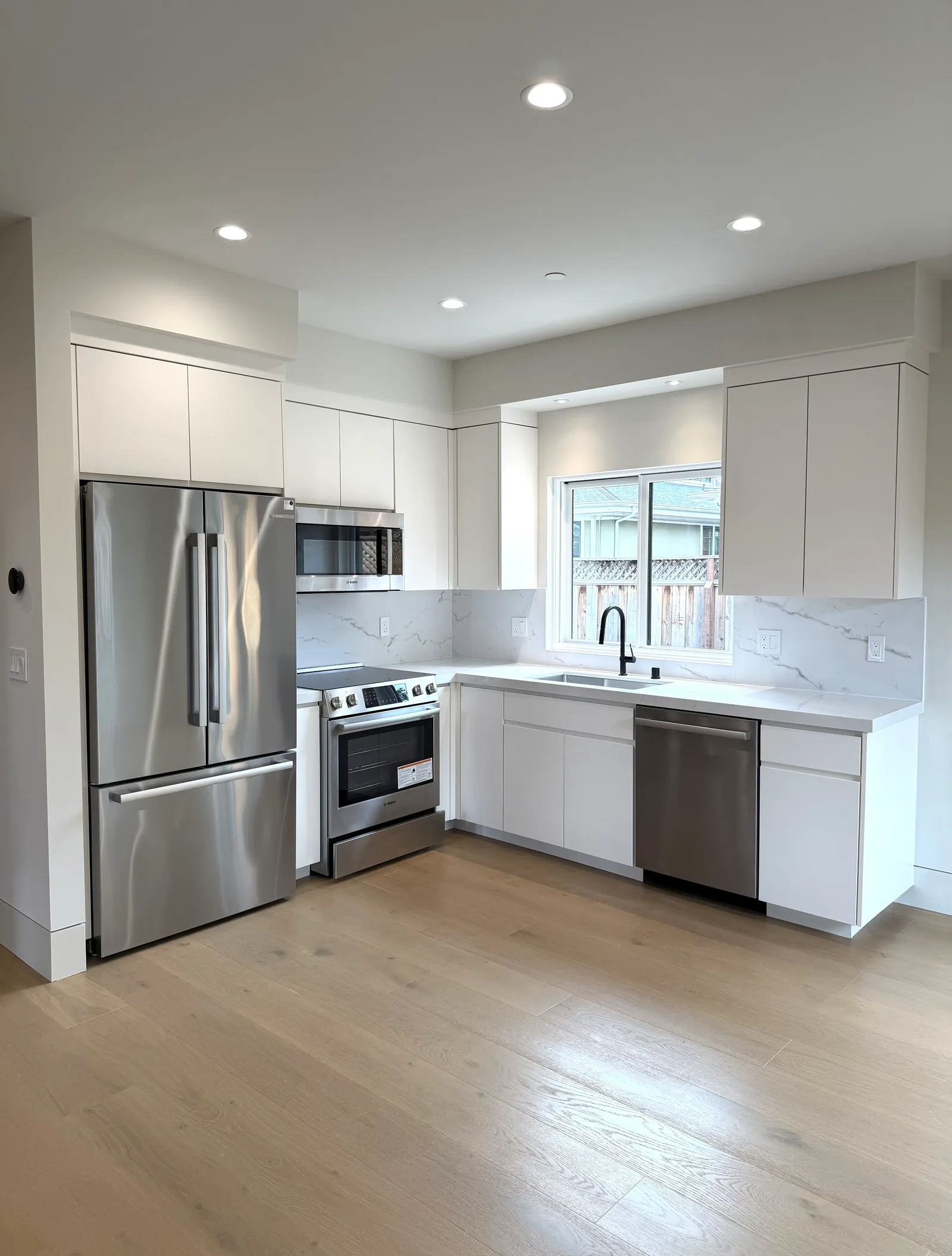 White flat panel kitchen with integrated stainless appliances in Los Altos