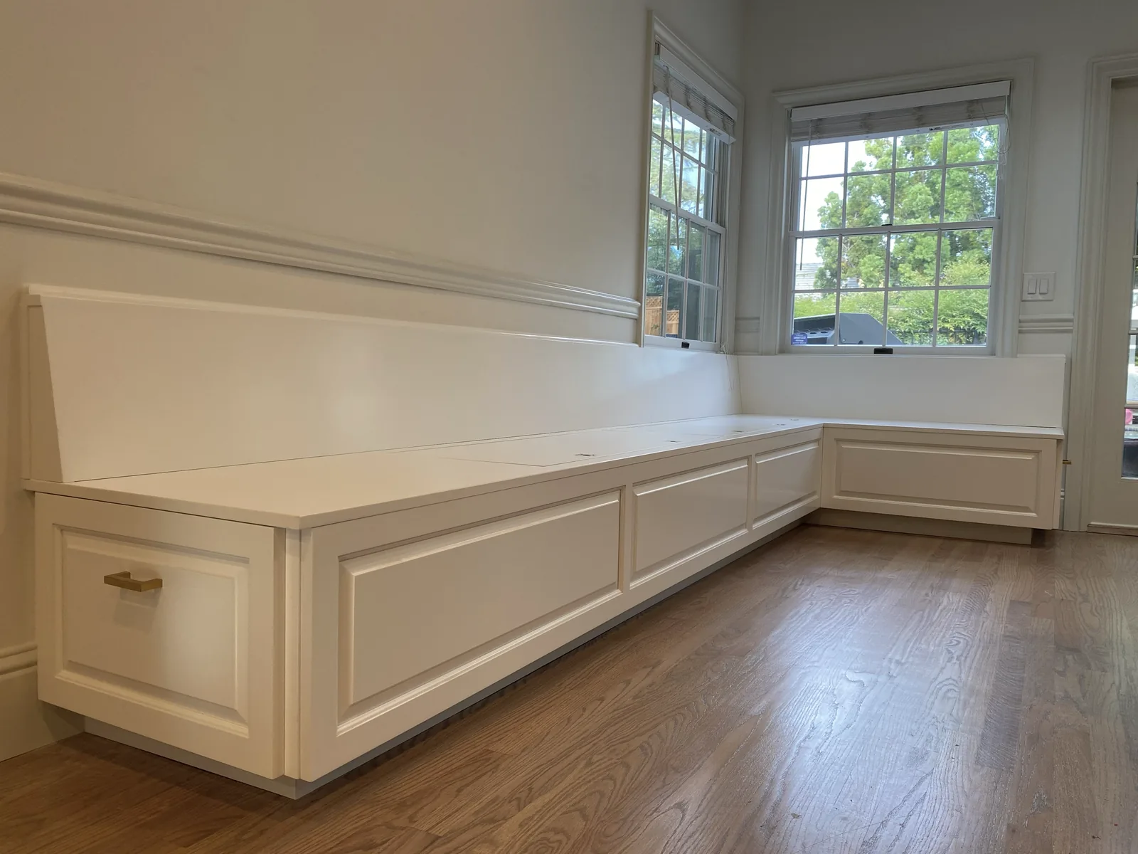 White built-in bench seating with lift-up storage along a window in Los Gatos