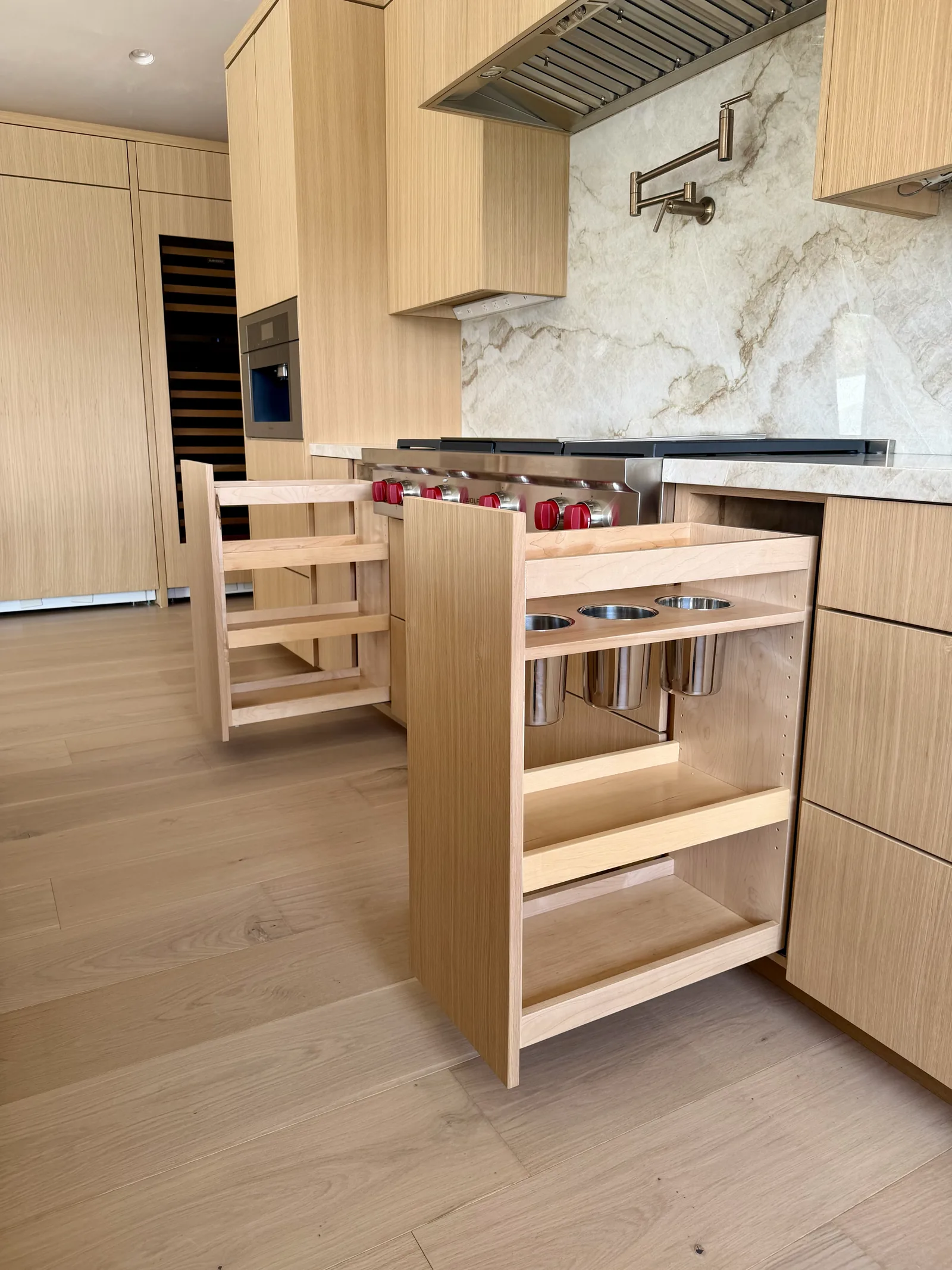 Narrow pull-out spice and utensil organizers beside a cooktop in Monterey