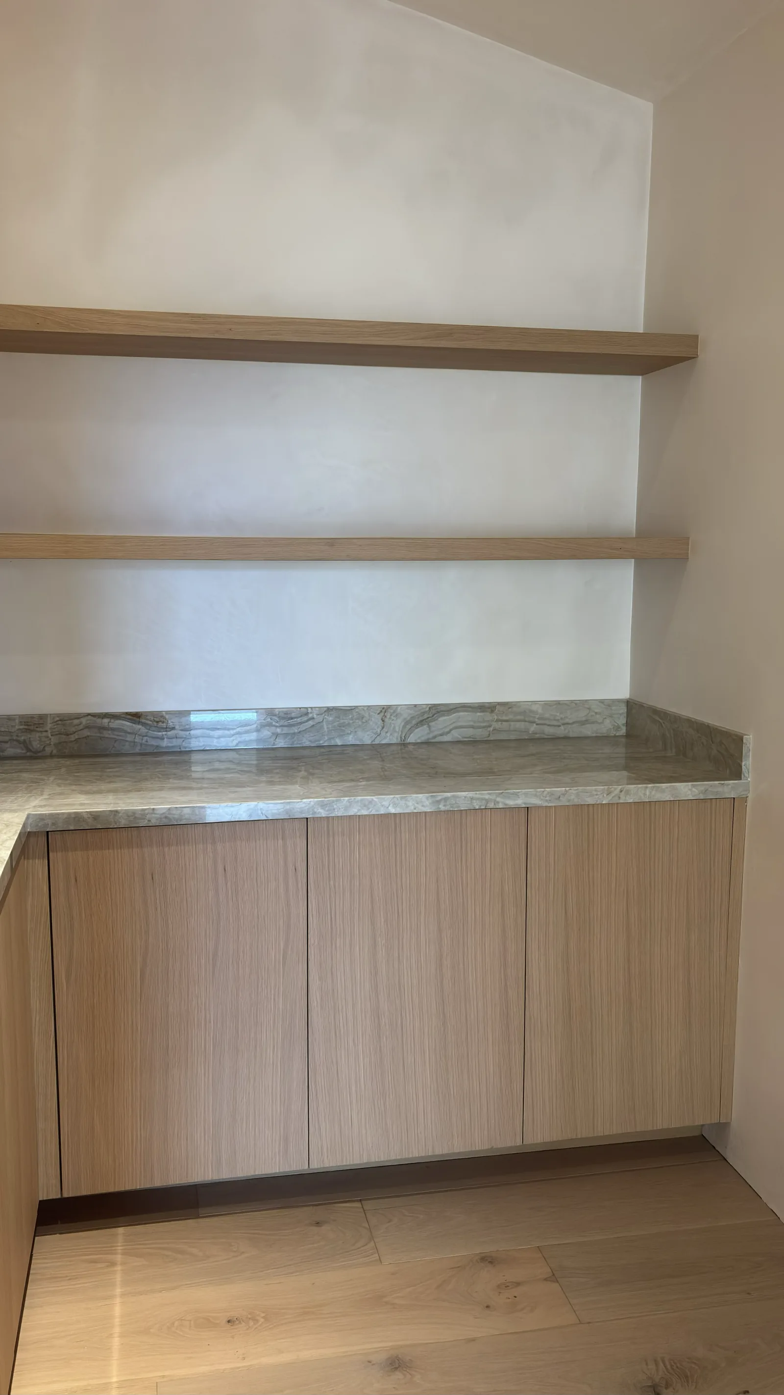 White oak cabinet run with a marble counter and floating shelves in Monterey