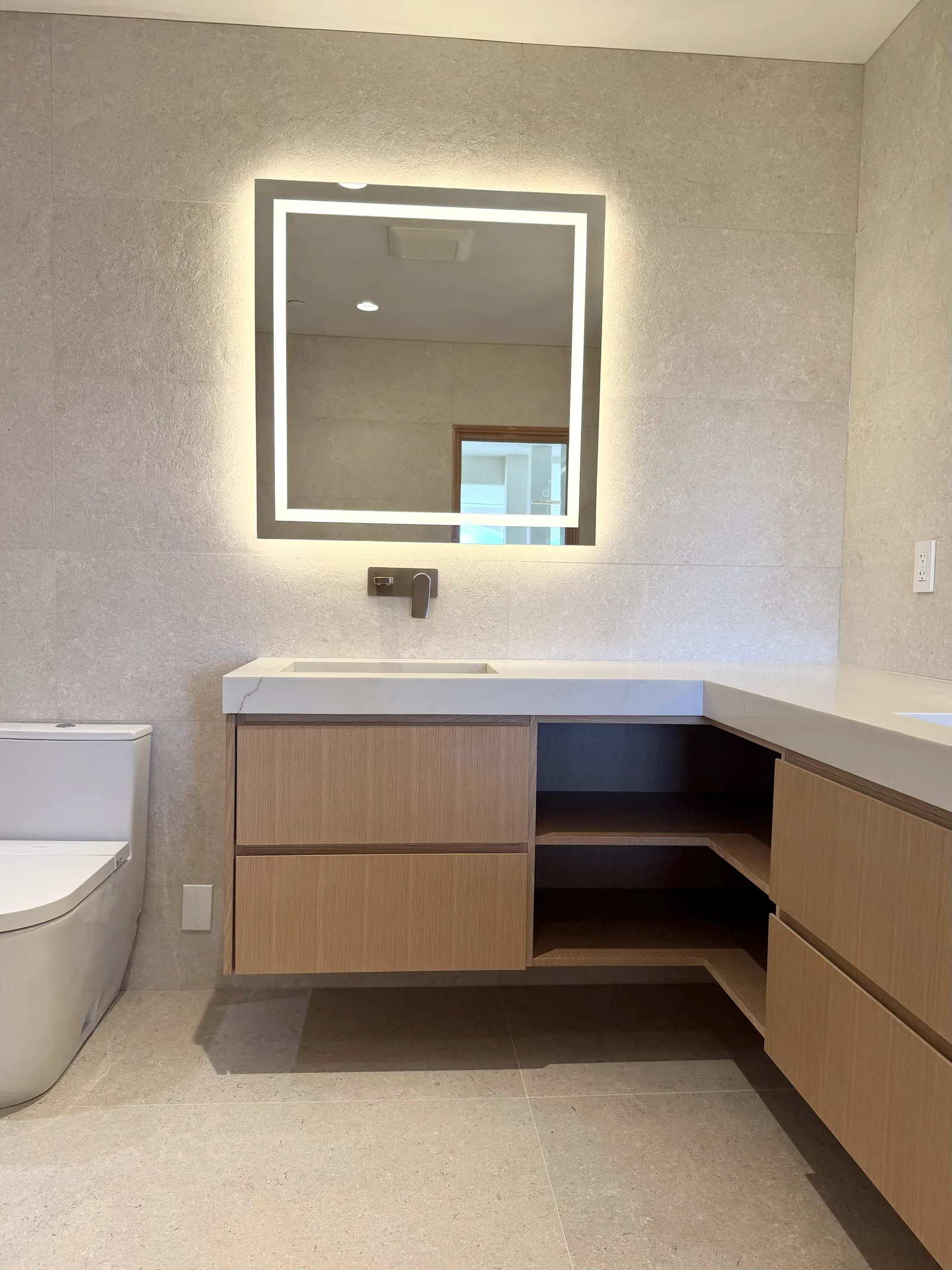 White oak floating vanity with open shelving and a lit mirror in Monterey