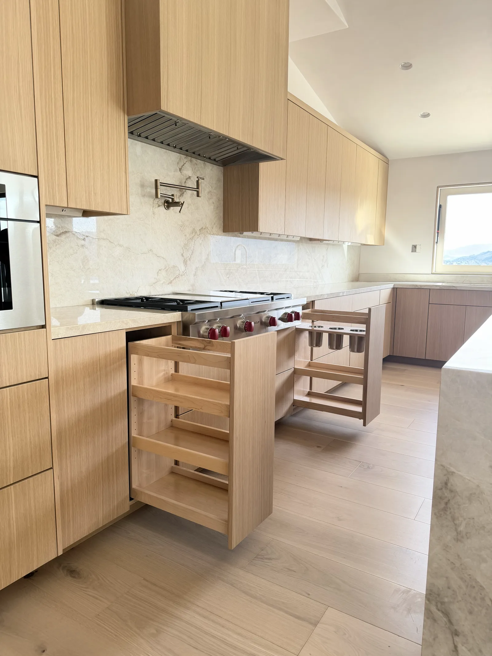 White oak kitchen with a full marble backsplash and pull-out organizers in Monterey