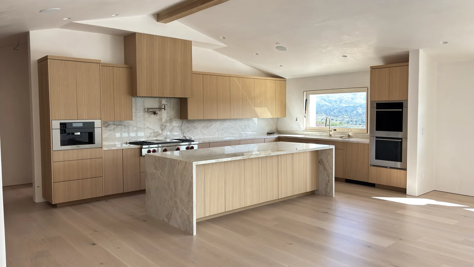 White oak flat panel kitchen with a marble waterfall island in a Monterey home