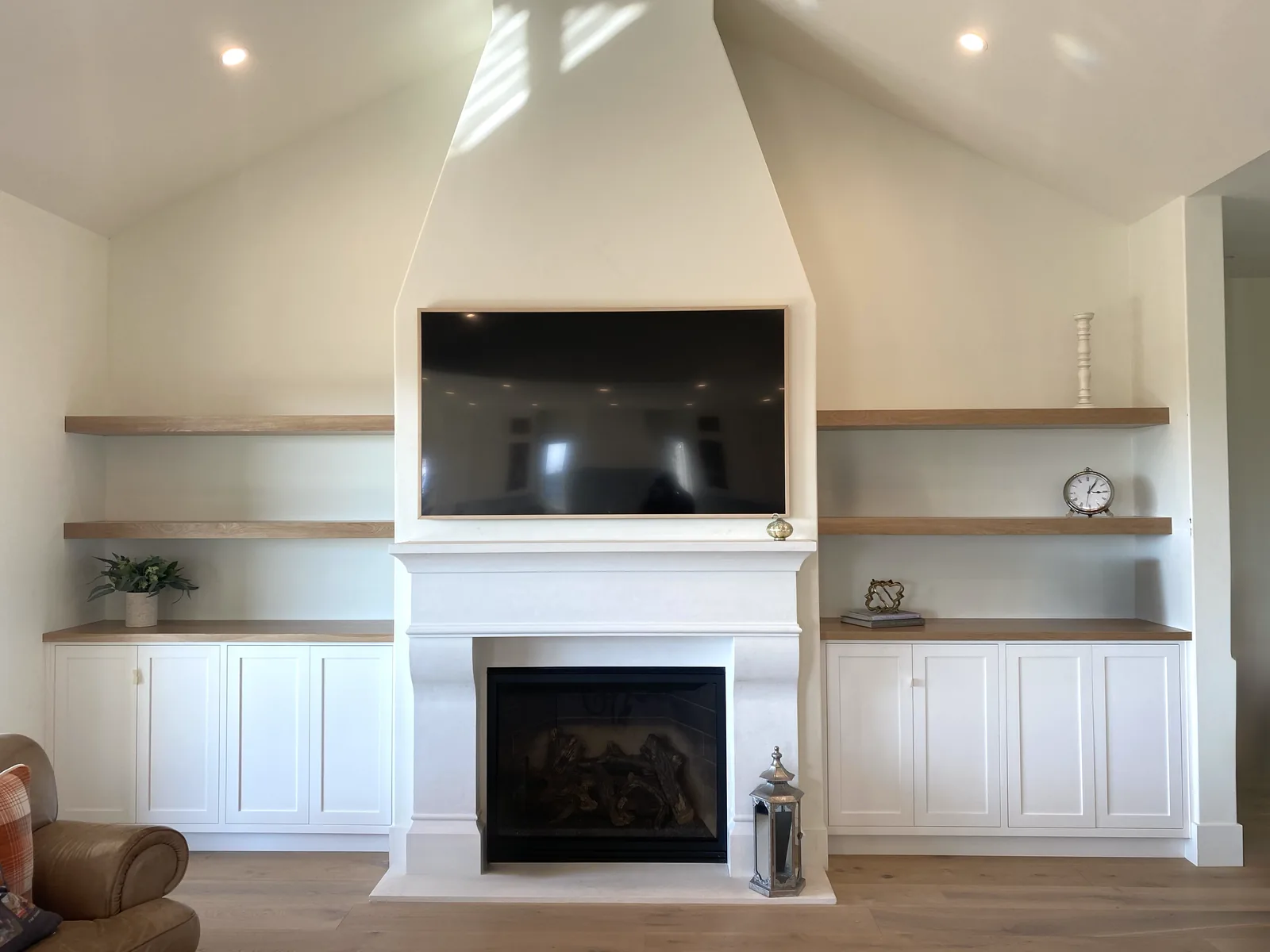 White fireplace surround with flanking cabinets and floating shelves in Morgan Hill