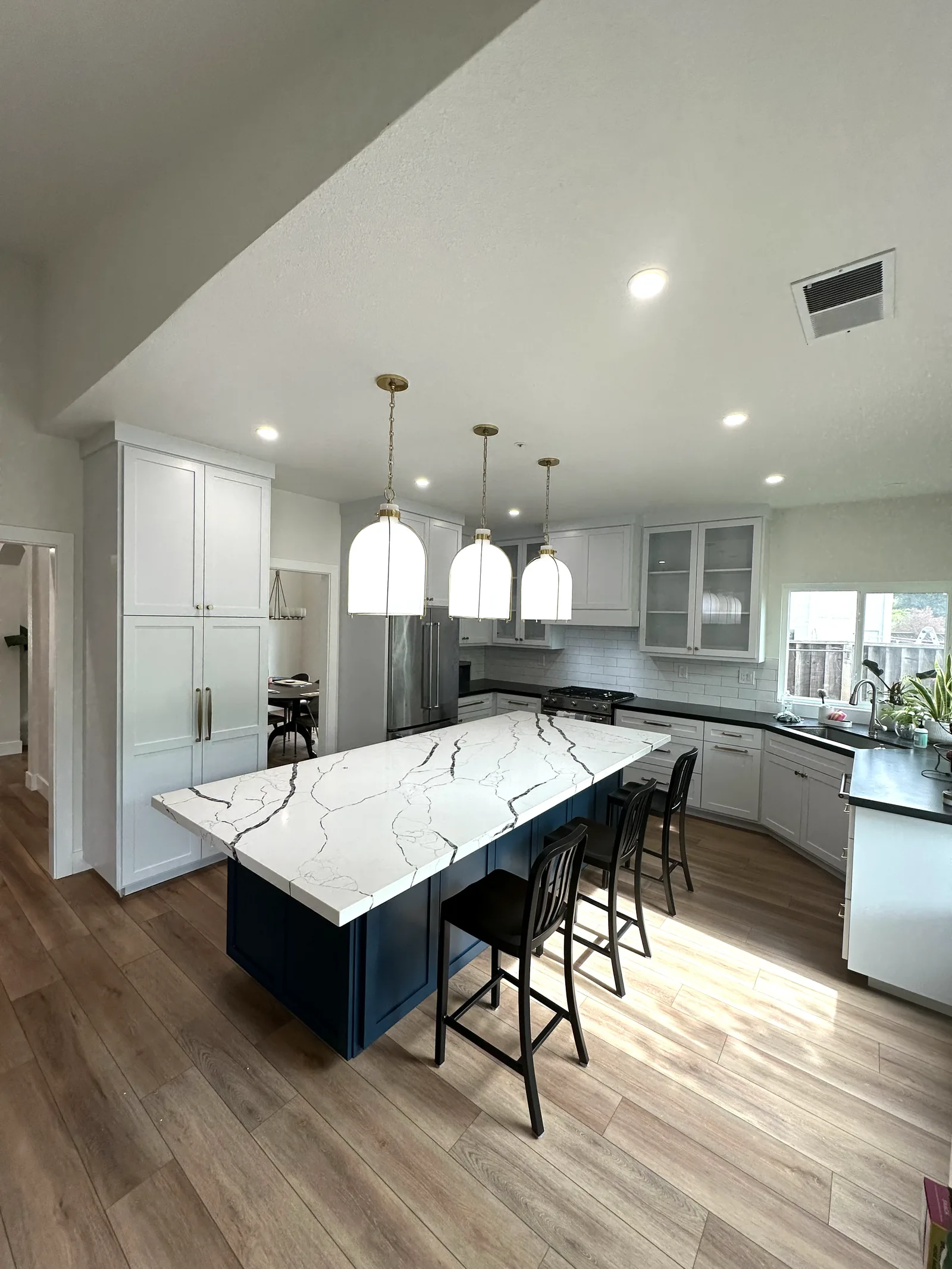 White shaker kitchen with a navy island and marble waterfall top in Morgan Hill