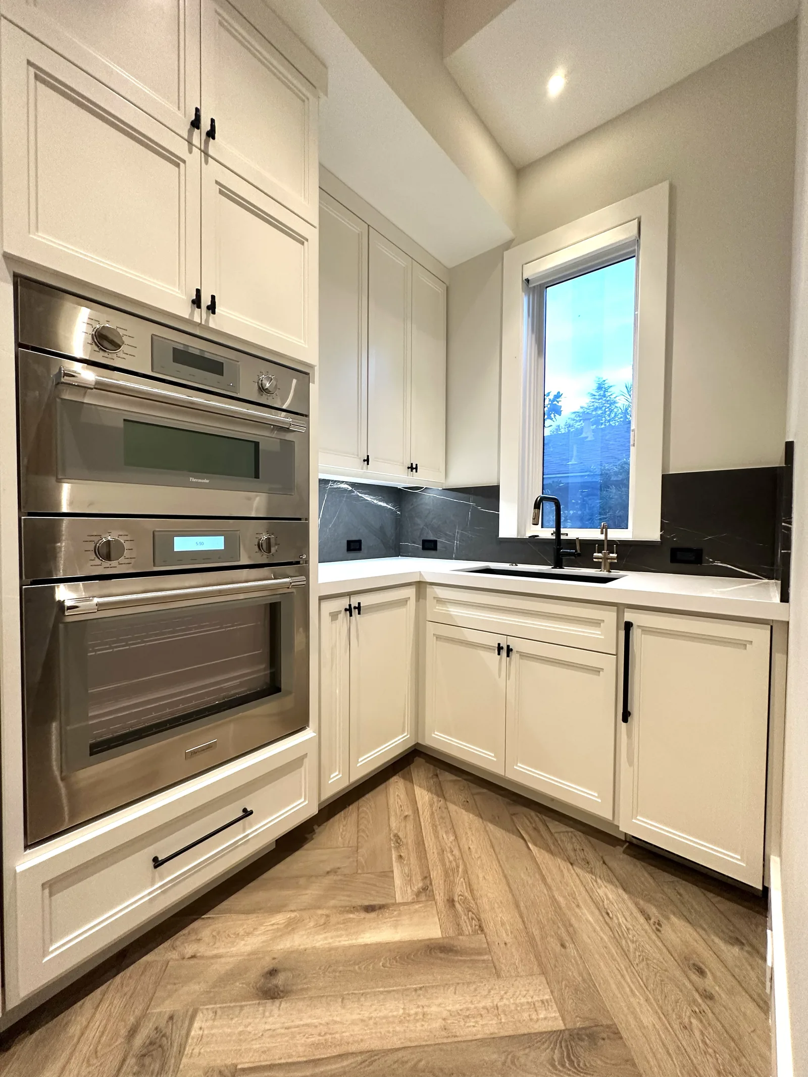 White painted kitchen with stacked double ovens and quartz counters in Palo Alto