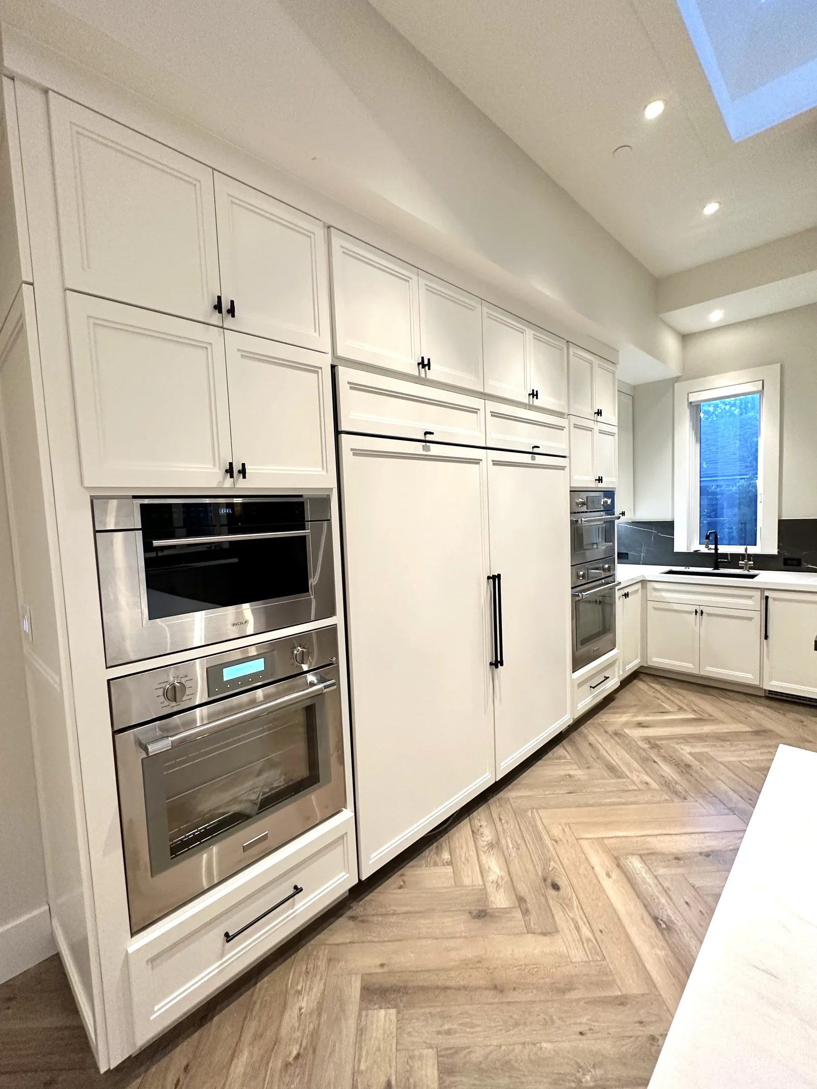 White kitchen with a fully integrated refrigerator and herringbone floor in Palo Alto