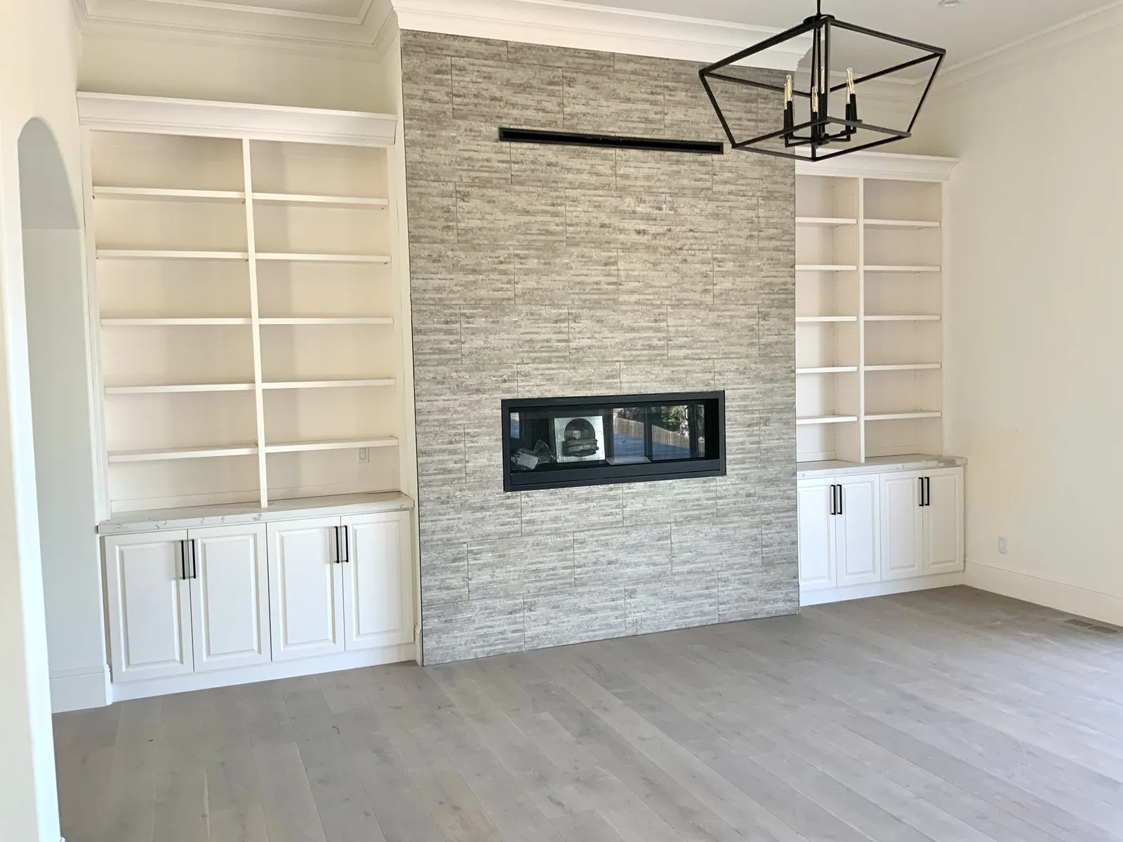 Stone fireplace wall flanked by white built-in bookcases in San Jose