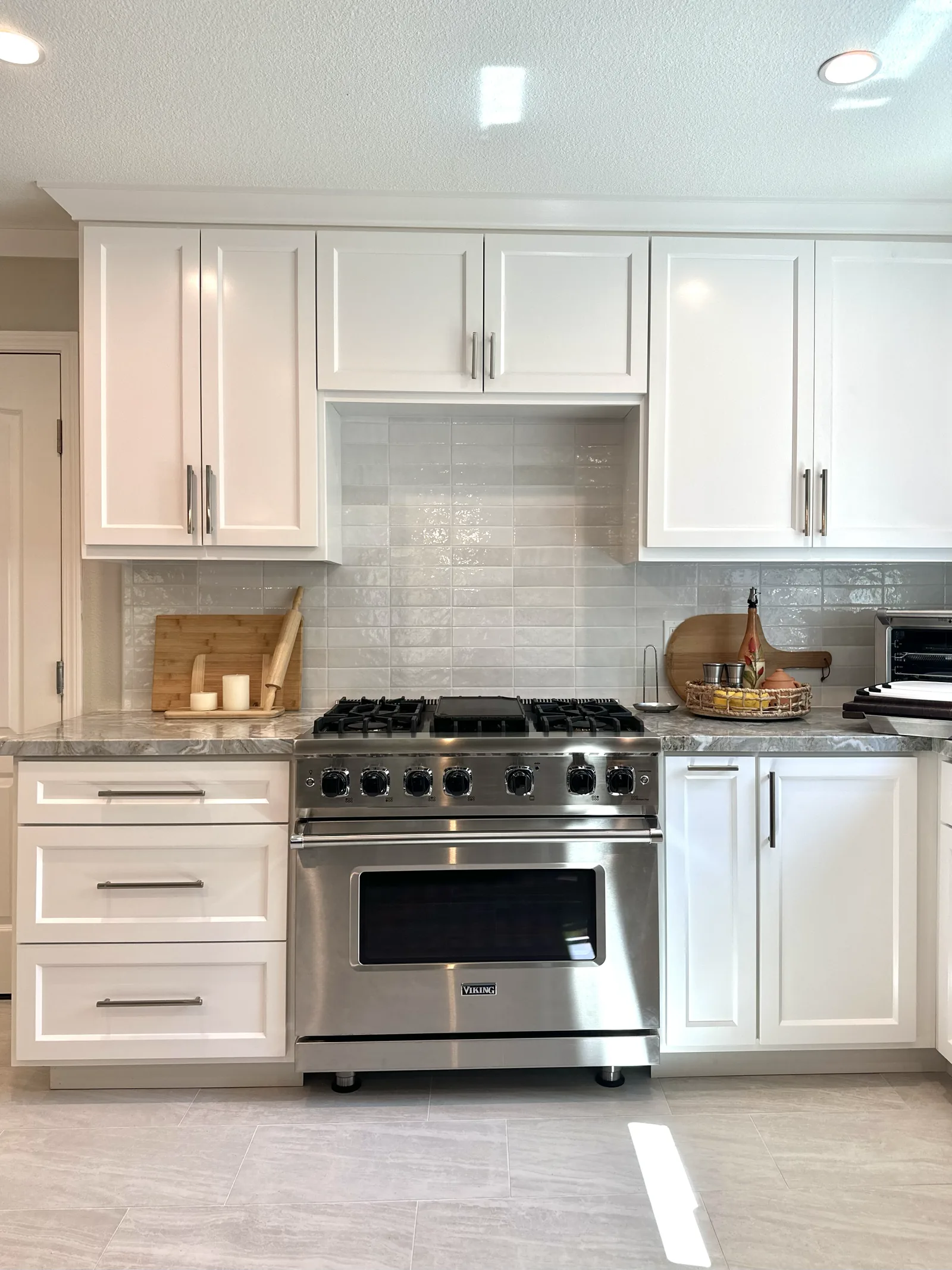 White shaker kitchen with a professional range and marble backsplash in San Jose