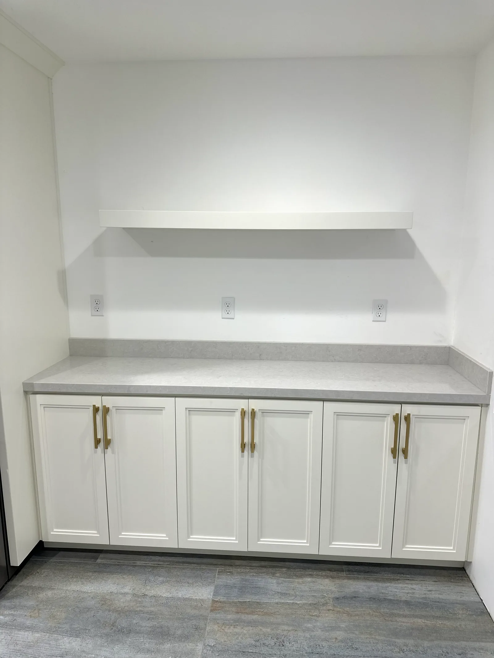 White kitchen cabinets with brass pulls and an open display shelf in Santa Clara