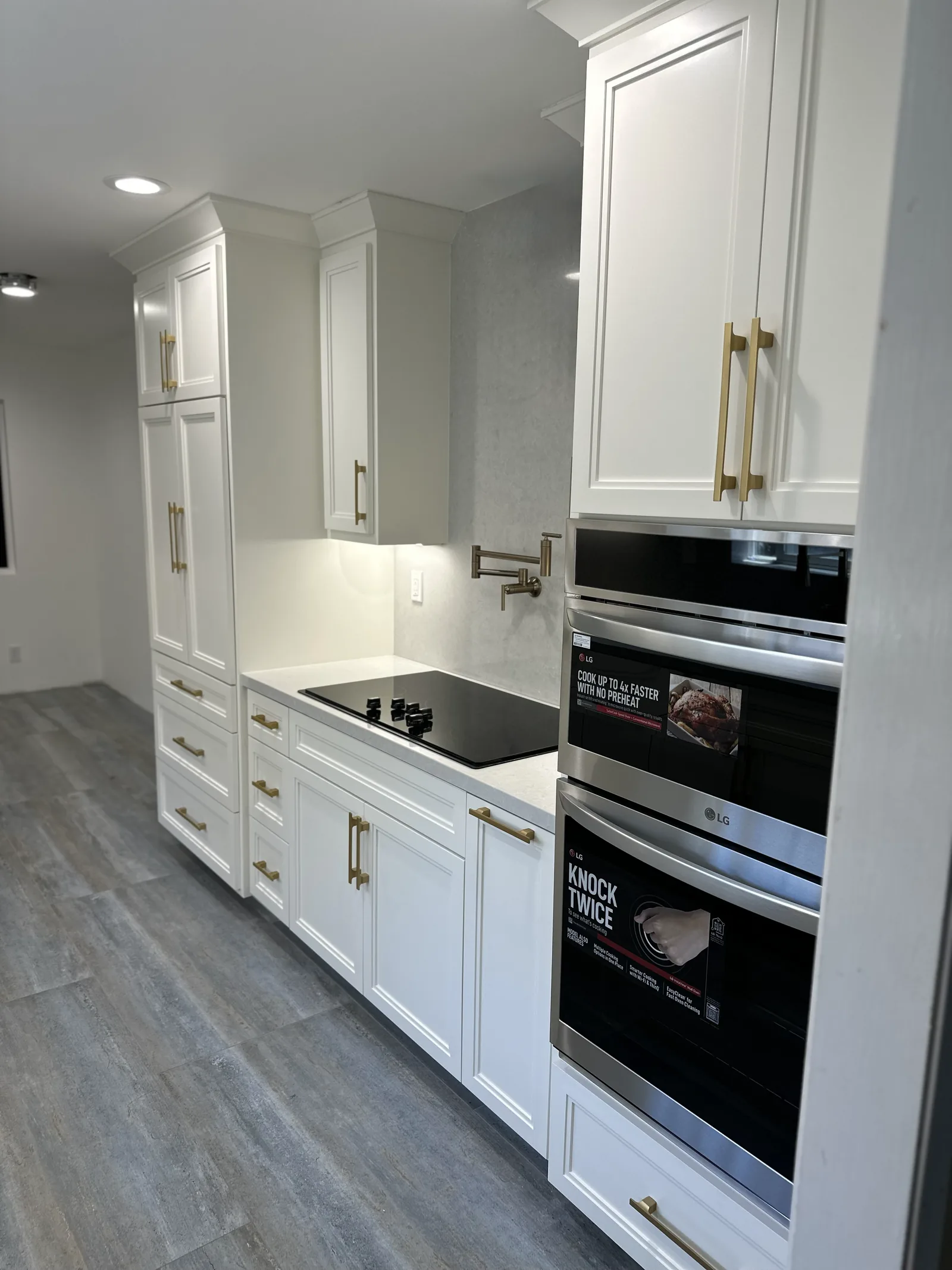 White kitchen with double wall ovens and brass hardware in Santa Clara