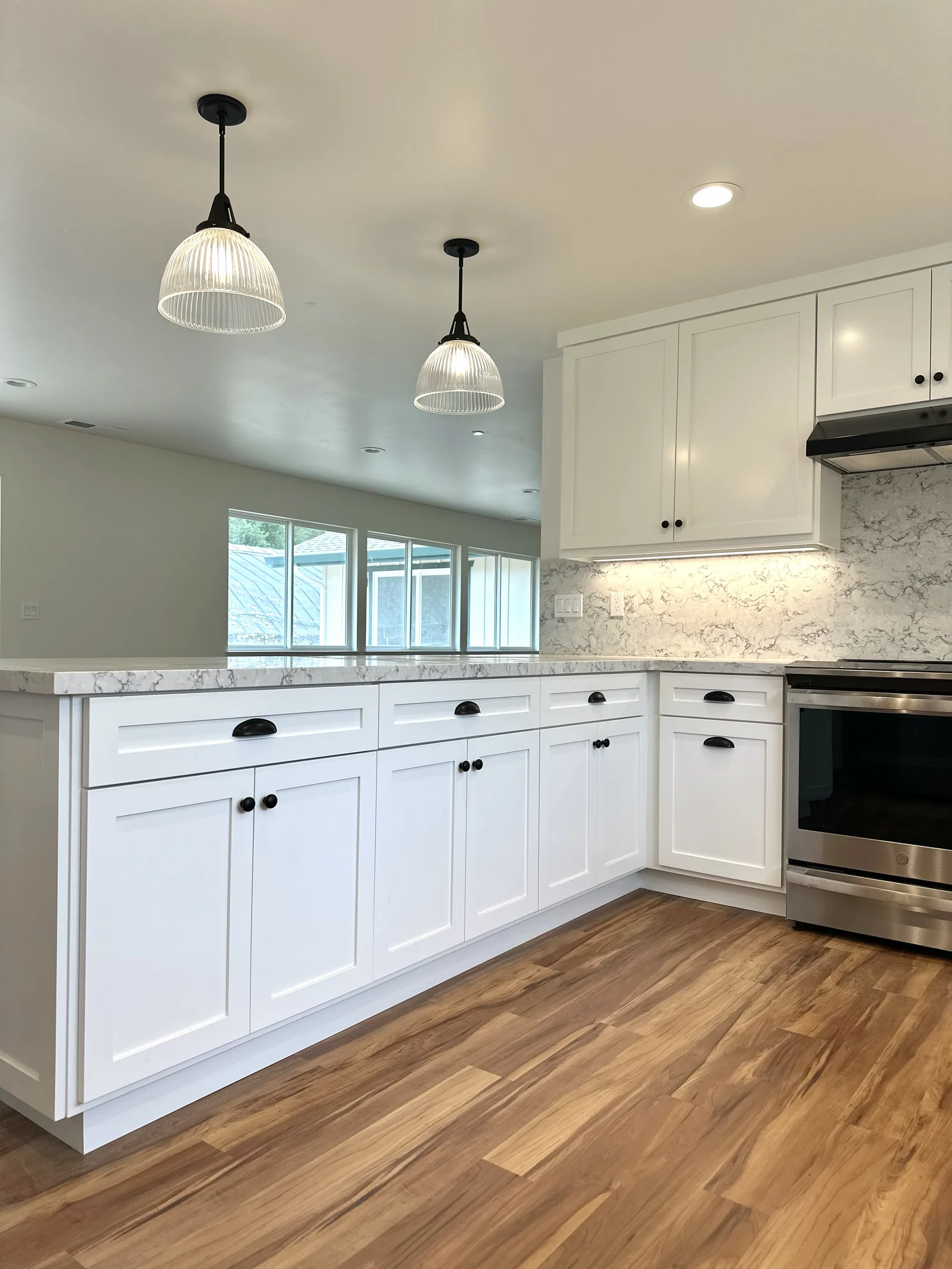 White shaker kitchen with quartz counters and a peninsula in Soquel